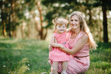 portrait of a daughter hugging mother on nature on summer day vacation. mom and girl playing in the 