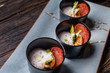 Lobster shrimp appetizer with parma ham, asparagus and white mousse sauce in black bowl on rustic wooden table 
