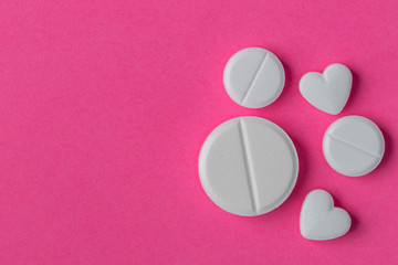 White pills set on pink color background.