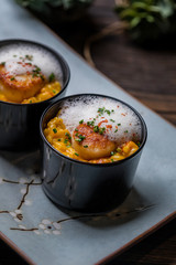 Wall Mural - Orange pumpkin risotto with scallop and foamy sauce in black bowl on rustic wooden table