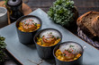 Orange pumpkin risotto with scallop and foamy sauce in black bowl on rustic wooden table