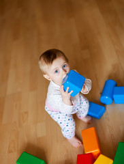  baby playing with plastic cubes on   floor in   room.