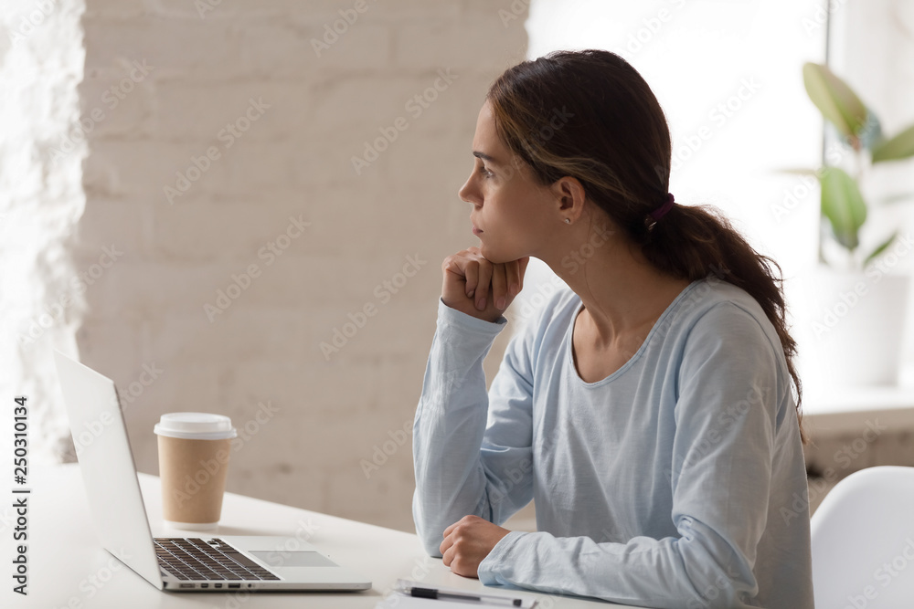 Concerned female sitting at workplace thinking looking away - obrazy, fototapety, plakaty 