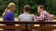 © motortion - Parents talking with son on bench in park, supporting teen in time of trouble
