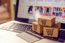 Shopping Online. Cardboard Box With A Shopping Cart Logo In A Trolley On A Laptop Keyboard Payment By Credit Card And Offers Home Delivery.