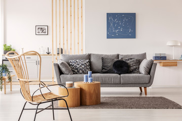 Wicker chair next to wooden block coffee table in fashionable living room interior