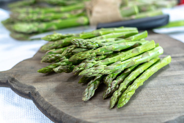 Fresh raw green asparagus vegetable on wooden plank, close up