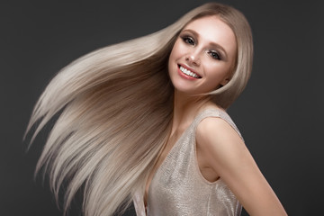 Beautiful blond girl in move with a perfectly smooth hair, and classic make-up. Beauty face.