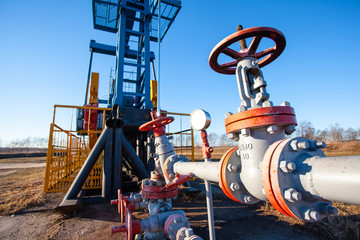 pipe and valve close up next to an aboveground oil producing tower