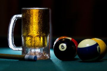 close up isolated cold frozen beer mug with billiard cues and balls on black background