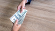© suphaporn - close up hand of business giving or paying money  US dollar bill