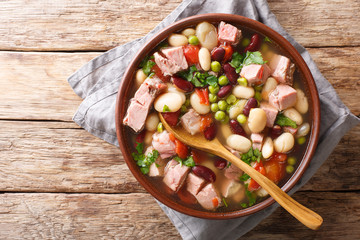 Wall Mural - Delicious bean soup with ham, tomatoes and herbs close-up in a bowl. horizontal top view