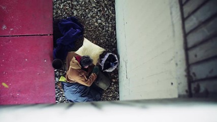 Wall Mural - A top view of homeless beggar man lying on the ground outdoors in city.