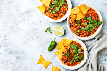 Vegetarian chili con carne with lentils, beans, nachos, lime, jalapeno. Mexican traditional dish