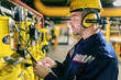 © dusanpetkovic1 - Young Caucasian worker in protective suit using tablet while checking machines in heating plant.