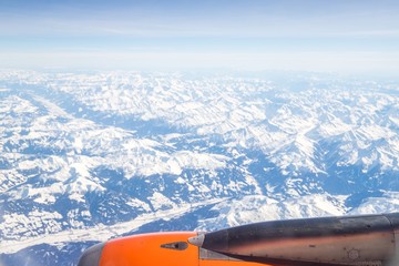 Wall Mural - Aerial view of snow covered mountains - snowy mountain peaks - high mountains - Alps out of a Airplane window 