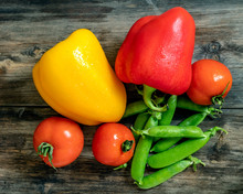 Top View Of Red And Yellow Bell Peppers, Tomatoes And Green Pea Pods On A Wooden Desk Close-up