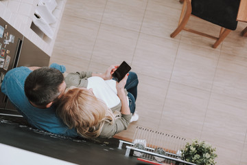 Wall Mural - Blond lady with cellphone spending time with husband at home