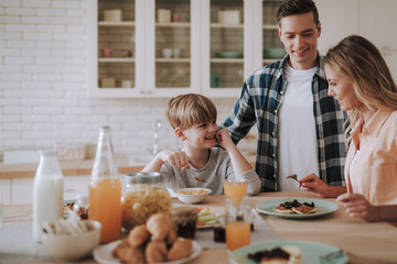 Happy family in the kitchen having breakfast and smiling