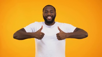 Wall Mural - Handsome black man smiling confidently, showing thumbs up on yellow background