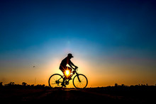 Silhouette Of Cyclist In Sunset Background.