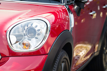 Close-up of detail headlight and hood modern red car.