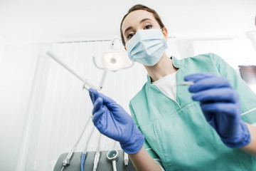 Wall Mural - selective focus of dentist in mask and latex gloves holding dental instruments