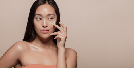 Woman applying beauty product on face