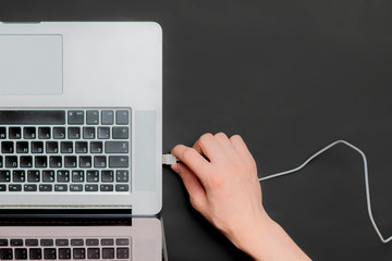 persons hand insert usb wire in a laptop isolated b