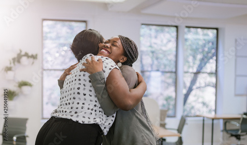 Two female black african freelancers embraced in a friendly hug in a modern co-w Tableau sur Toile