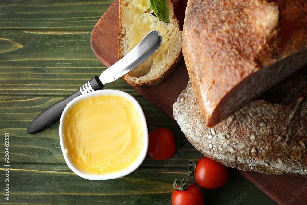 Cutting board with tasty bread and spread on wooden table