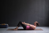 Fototapeta  - Young woman practicing yoga asana Ardha Navasana exercise at the yoga studio