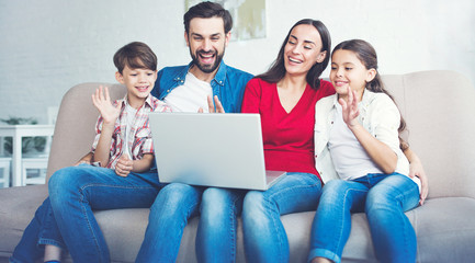 Wall Mural - Happy beautiful family with laptop on the couch at home in casual clothes