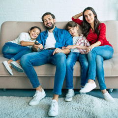 Wall Mural - Beautiful happy family watch TV on the couch at home and smiling