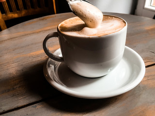 Wall Mural - Cappuchino on the wooden table in cafe