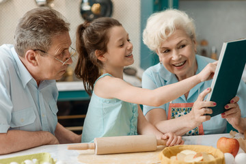 Wall Mural - Granddaughter and grandparents cooking together