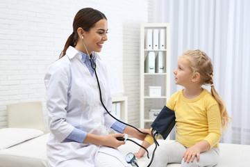 Canvas Print - Little girl visiting doctor in hospital. Measuring blood pressure and checking pulse