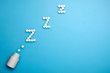 Tablets and pills. Letters ZZZ from the pills flying out of the bottle. Sleeping pills on a blue background.