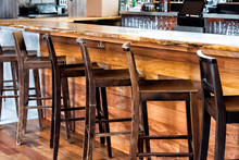 Row Of Empty Wooden Vintage Bar Stools By Counter In Drink Establishment Pub During Day Pattern Closeup Rustic Retro Wood And Nobody