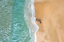 Small Group Of Wave Surfers And Surf Boards Standing On A Sandy Beach In Front Of The Mediterranean Sea - Top Down Aerial Image.