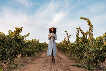Young woman walking in a path in the middle of a vineyard