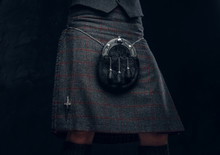 Traditional Scottish Costume. Kilt And Sporran. Studio Photo Against A Dark Textured Wall
