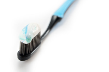 black toothbrush with the minty color of toothpaste on a light background