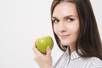 Young beautiful brunette girl on a white background holding a fresh green apple.