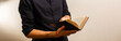 Missionary man holds his bible with interlocked fingers to pray.