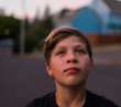 © Cavan Images - Close up of thoughtful boy standing on road during sunset