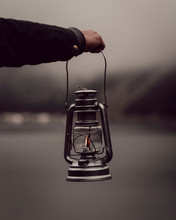 Man's Hand Holding Lantern By Lake