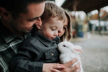 Family Playing With Rabbit On Farm