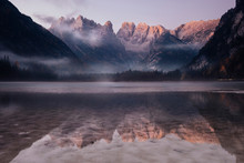 Scenic View Of Mountains Reflecting In Lake Against Sky During Sunrise