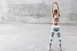 Leinwandbild Motiv Fitness sport woman in fashion sportswear doing stretching exercise over gray wall